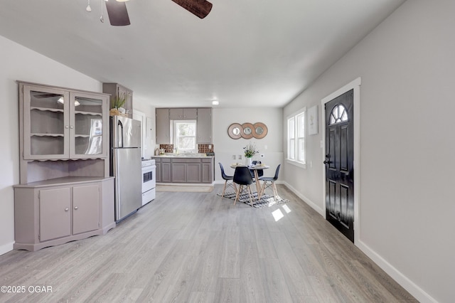 entryway with light wood-style floors, ceiling fan, baseboards, and a wealth of natural light