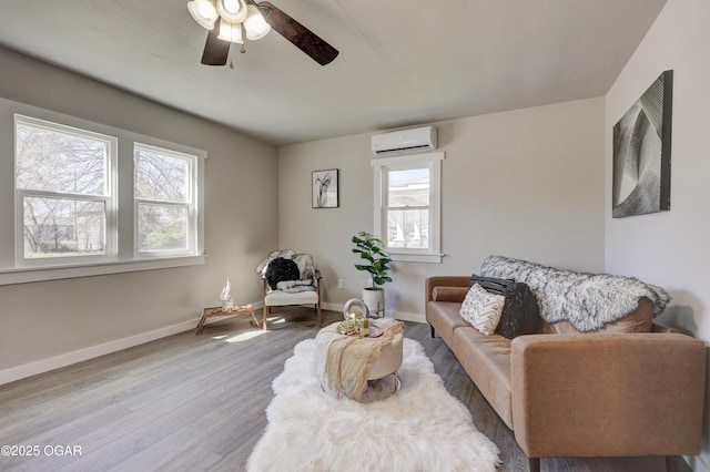 living room with a wall mounted air conditioner, baseboards, a ceiling fan, and wood finished floors