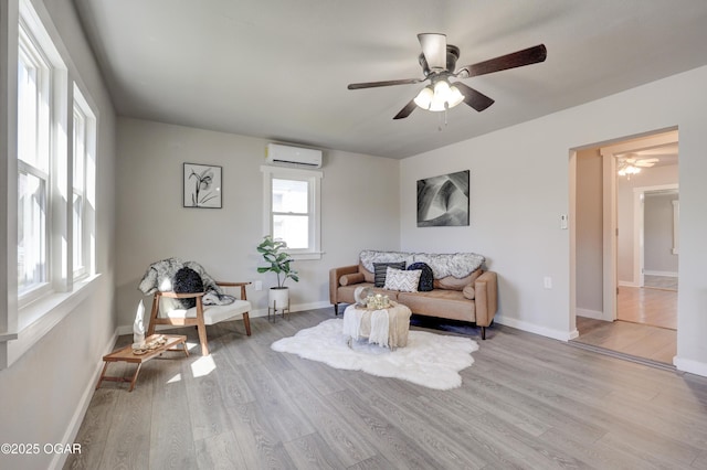 living area with light wood-type flooring, a ceiling fan, a wall mounted AC, and baseboards