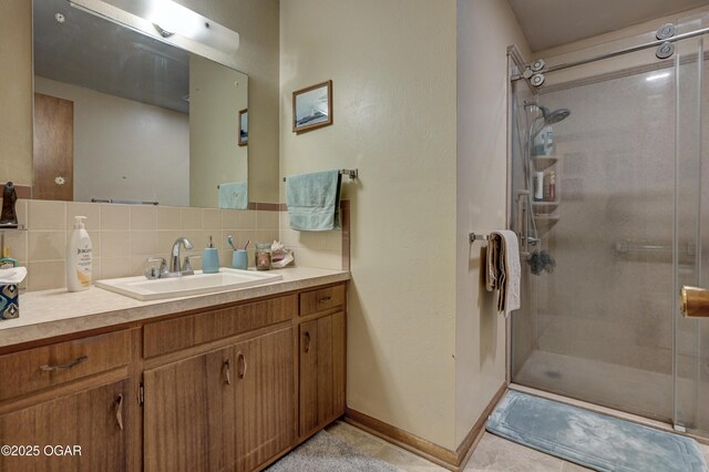 full bath featuring a shower stall, tasteful backsplash, vanity, tile patterned flooring, and baseboards