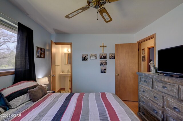 bedroom with a sink, wood finished floors, connected bathroom, and ceiling fan