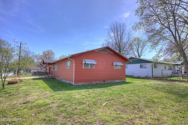 view of side of property featuring crawl space, fence, and a lawn