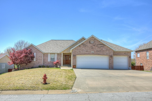 ranch-style house with roof with shingles, a front yard, brick siding, an attached garage, and driveway