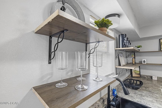 interior space featuring a sink, open shelves, and a textured wall