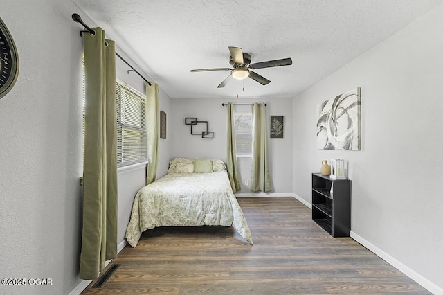 bedroom featuring baseboards, multiple windows, wood finished floors, and a ceiling fan