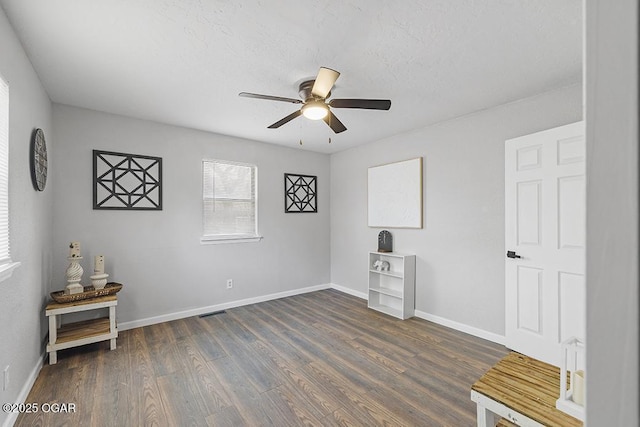 unfurnished room featuring visible vents, ceiling fan, baseboards, and dark wood-style floors