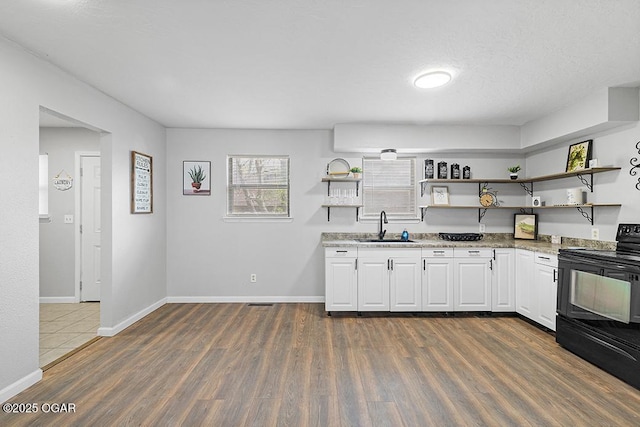 kitchen with dark wood-type flooring, black range with electric cooktop, a sink, and open shelves