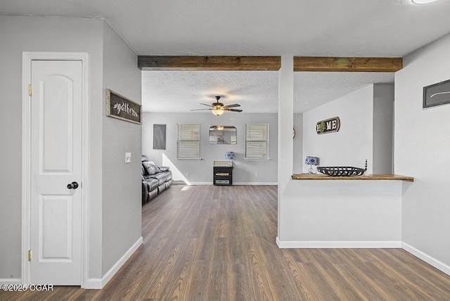 interior space featuring beam ceiling, baseboards, wood finished floors, and a textured ceiling