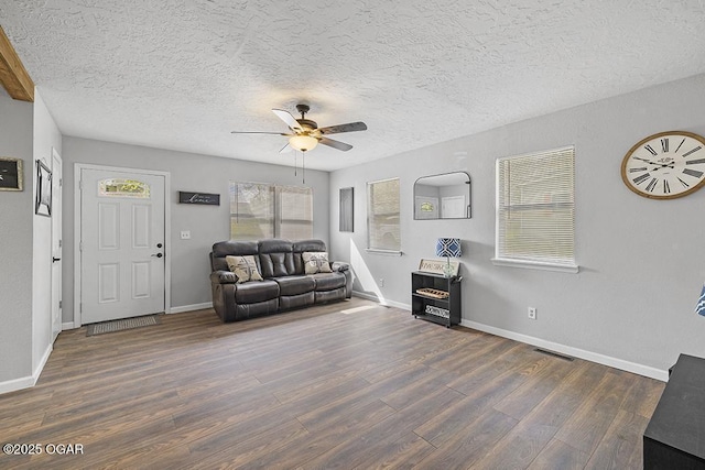 living room featuring visible vents, a textured ceiling, a ceiling fan, and wood finished floors