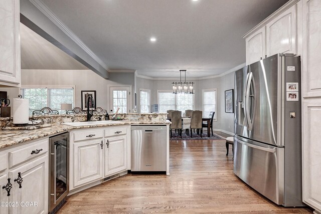 1000 Oakmont Dr, Joplin, MO 64804 - kitchen featuring light wood-style floors, a peninsula, appliances with stainless steel finishes, a sink, and wine cooler