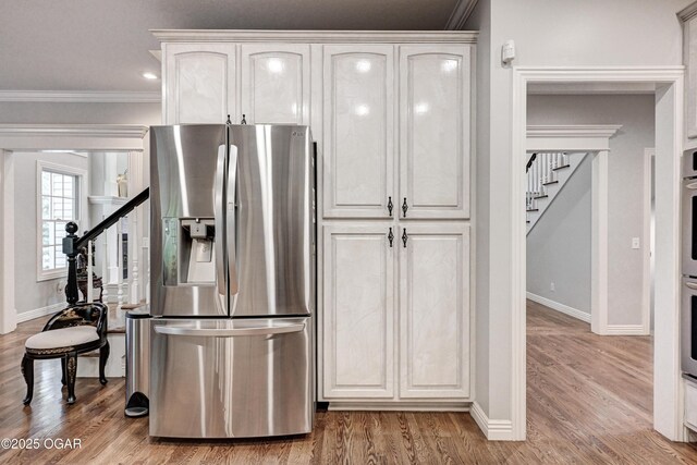 1000 Oakmont Dr, Joplin, MO 64804 - kitchen with baseboards, white cabinets, appliances with stainless steel finishes, crown molding, and wood finished floors