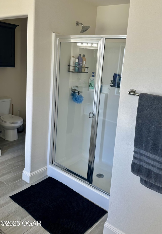 full bath with baseboards, a shower stall, and toilet