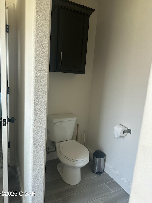 bathroom featuring baseboards, toilet, and wood finished floors