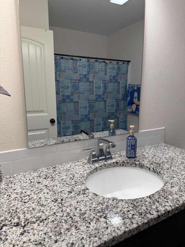 full bath with vanity, tasteful backsplash, a textured wall, and a shower with shower curtain