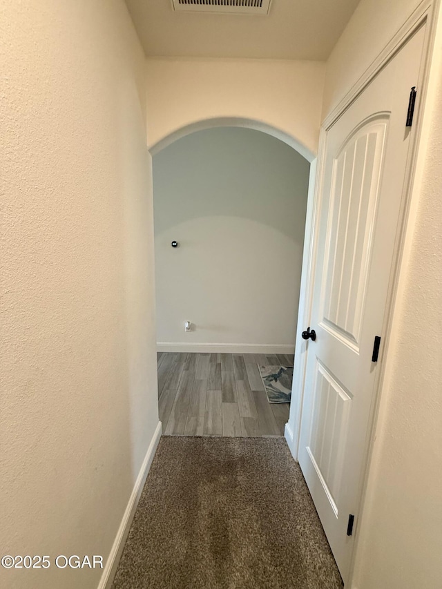 hall with arched walkways, baseboards, carpet, and visible vents