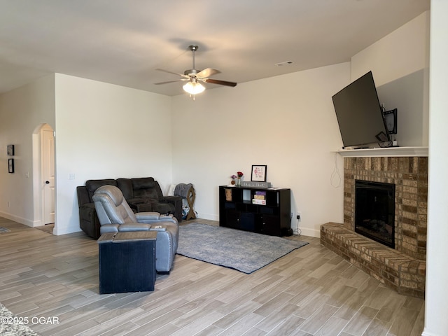 living area with arched walkways, ceiling fan, and light wood-type flooring