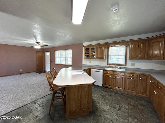 kitchen with white appliances, a kitchen breakfast bar, a sink, open floor plan, and brown cabinets
