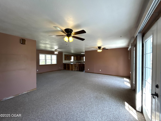 unfurnished living room featuring ceiling fan, baseboards, and carpet