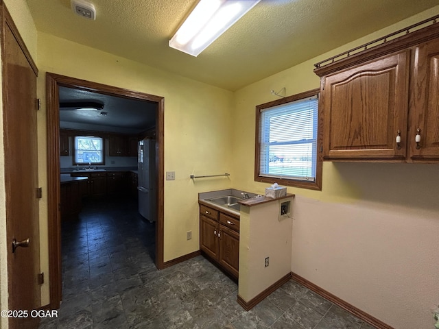 washroom with laundry area, a sink, baseboards, and a textured ceiling