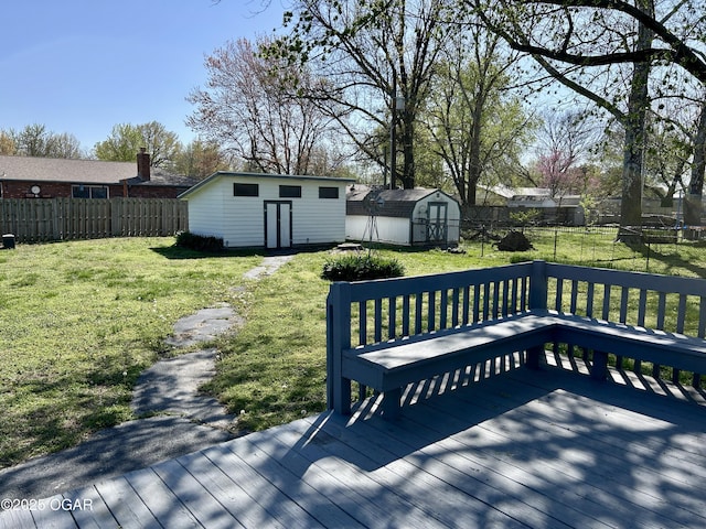 wooden deck featuring a yard, a fenced backyard, an outdoor structure, and a storage unit