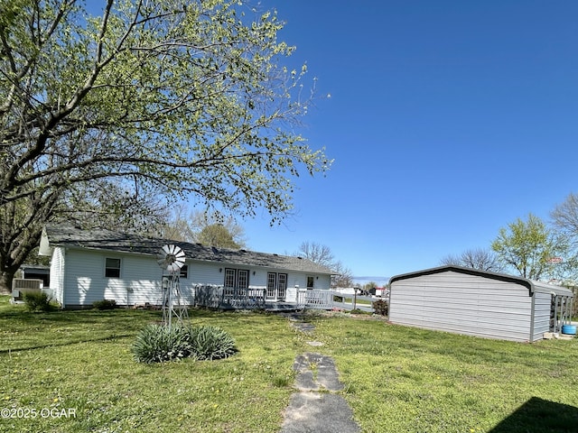rear view of property with a yard, a wooden deck, and an outbuilding