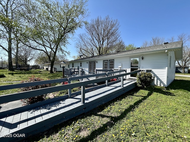 rear view of property featuring a yard and a wooden deck