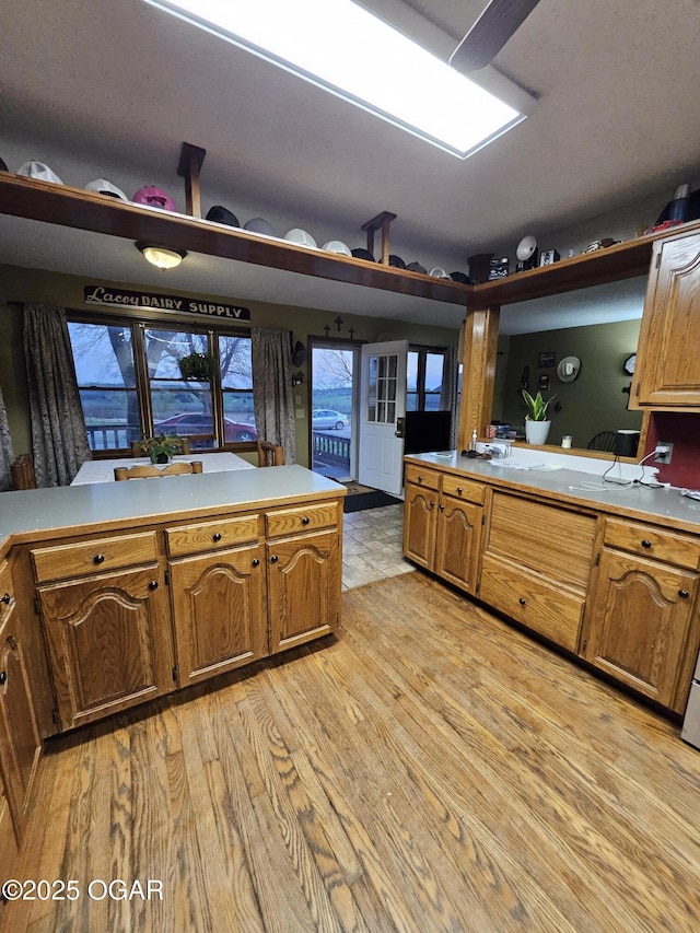 kitchen featuring brown cabinets, light wood-style floors, light countertops, and a peninsula