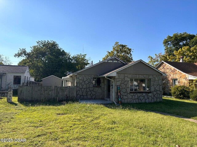 view of front of house with a front yard, fence, and stone siding