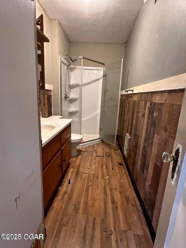 full bath with toilet, a stall shower, wood finished floors, and vanity