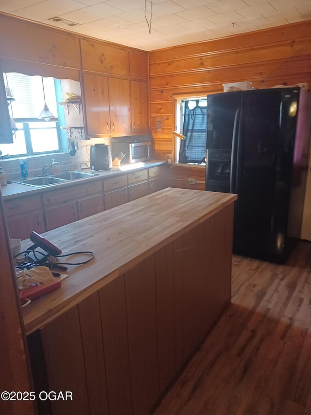 kitchen featuring light wood-style flooring, a sink, black fridge with ice dispenser, and a wealth of natural light