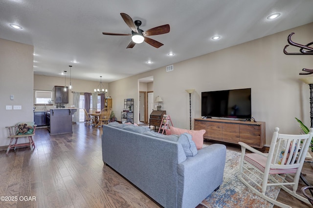 living room featuring ceiling fan with notable chandelier, dark wood finished floors, visible vents, recessed lighting, and baseboards