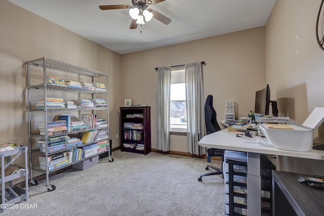 carpeted office space featuring baseboards and a ceiling fan