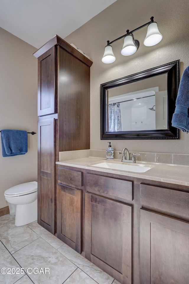 bathroom with toilet, vanity, and marble finish floor
