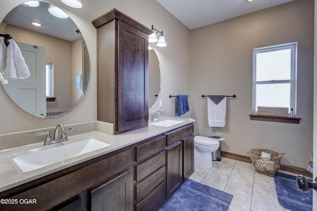 full bathroom featuring a sink, toilet, and double vanity