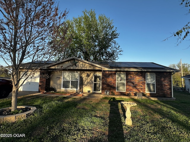 2027 P St SW, Miami, OK 74354 - ranch-style house featuring a front yard, solar panels, an attached garage, brick siding, and driveway