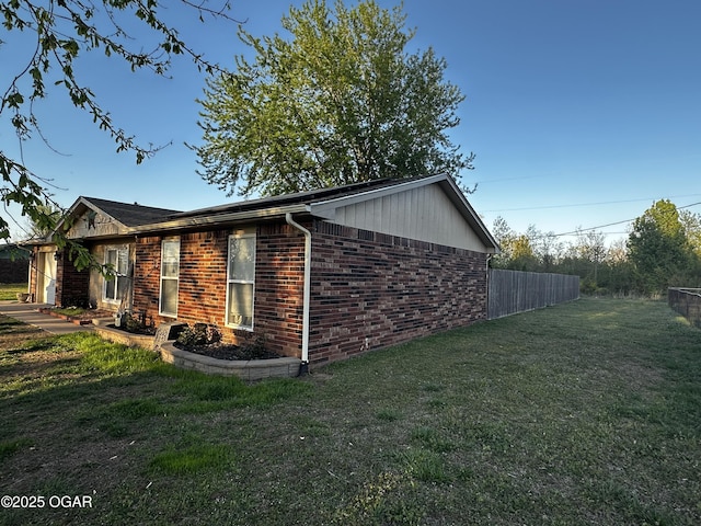 2027 P St SW, Miami, OK 74354 - view of side of property with brick siding, fence, and a lawn