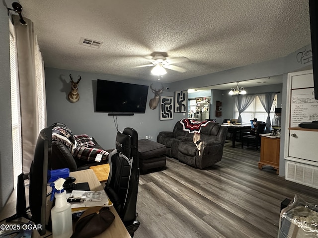 2027 P St SW, Miami, OK 74354 - living area featuring a textured ceiling, ceiling fan with notable chandelier, dark wood-style flooring, and visible vents