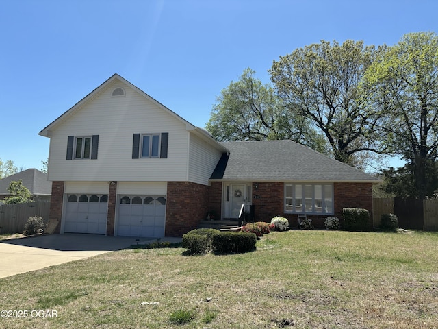 split level home with a front yard, an attached garage, fence, brick siding, and driveway