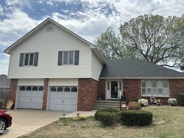 split level home featuring a garage, a front lawn, brick siding, a shingled roof, and driveway