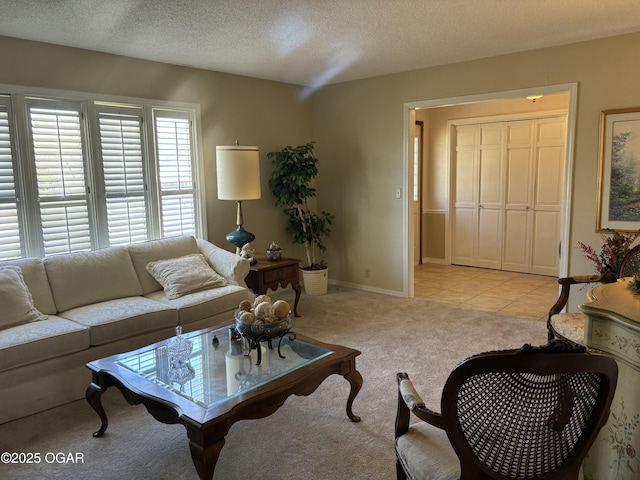 living room featuring light tile patterned flooring, a textured ceiling, light colored carpet, and baseboards