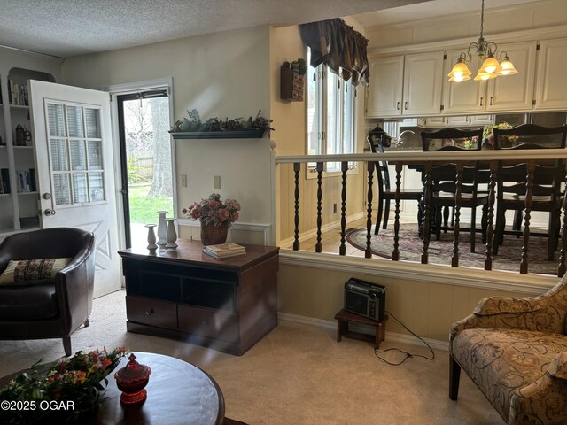 interior space featuring light carpet, an inviting chandelier, baseboards, and a textured ceiling