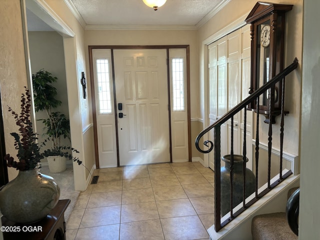 foyer with light tile patterned floors, ornamental molding, visible vents, stairway, and baseboards