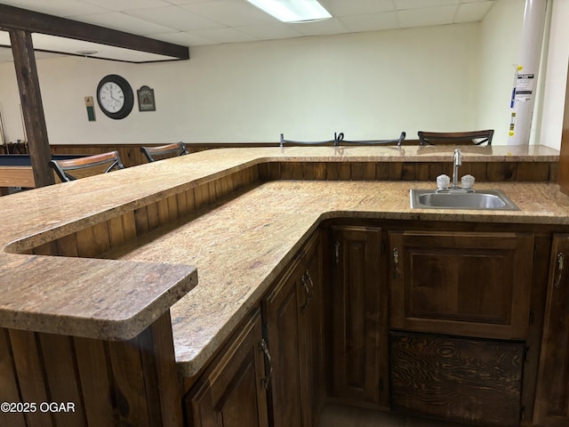 bar with a paneled ceiling, a sink, and a community bar