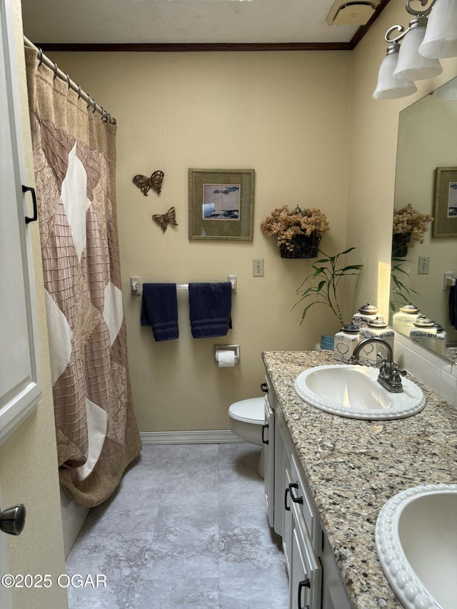 bathroom featuring toilet, crown molding, double vanity, and a sink