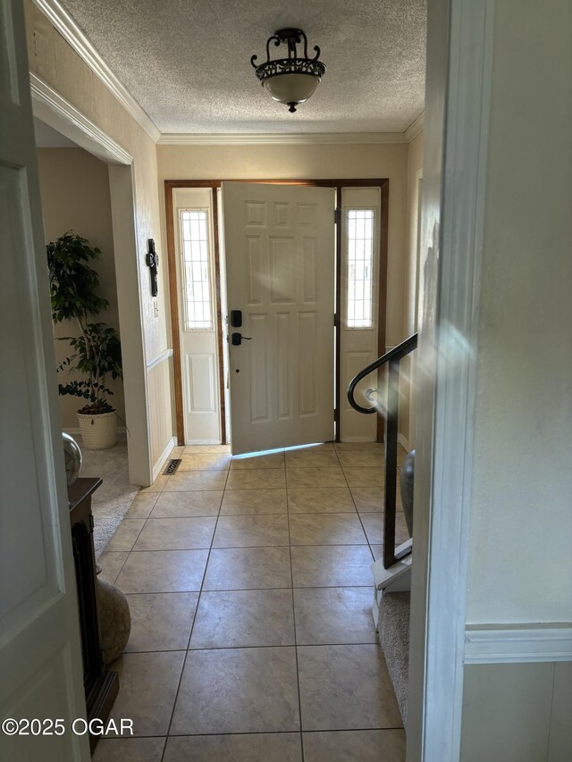 tiled entryway featuring crown molding, plenty of natural light, and a textured ceiling
