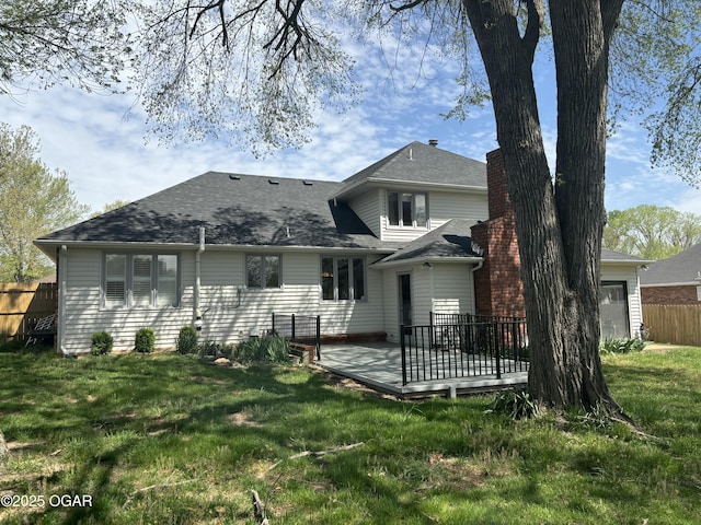 rear view of property featuring a yard, fence, and a shingled roof