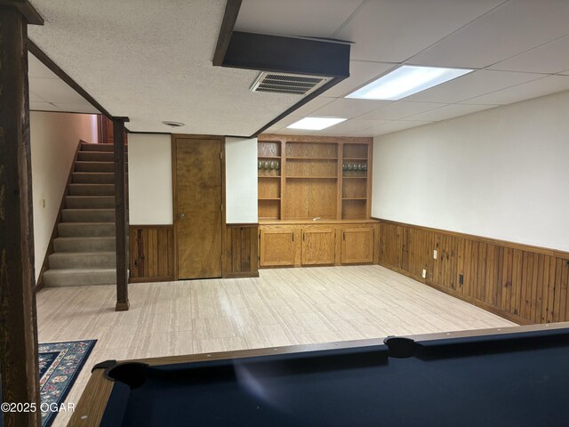 interior space featuring wooden walls, visible vents, and a wainscoted wall