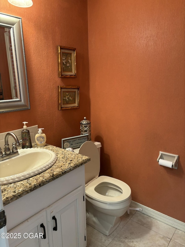 bathroom with tile patterned flooring, vanity, baseboards, and toilet