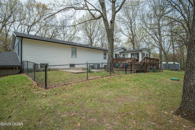 rear view of house featuring an outbuilding, central air condition unit, a yard, fence private yard, and a deck