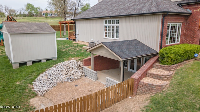 view of property exterior featuring a storage unit, a patio area, an outbuilding, a lawn, and french doors